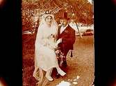 Brudpar, bruden helt i vitt, med myrtenkrona och lång slöja, brudgummen i bonjour och cylinderhatt.
Gustaf Andersson