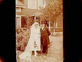 Brudpar, bruden helt i vitt, med lång slöja. Brudgummen i bonjour och hög hatt.
Carl Vallin