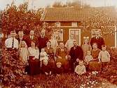 En och en halvvånings bostadshus. Släktgrupp 20 personer framför huset.Johan Blomberg