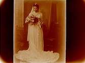 Brud, med vit klänning, krona och slöja, brudbukett.
Sam Lindskogs familjebild.
