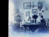 Rumsinteriör, en kvinna och två barn.Sam Lindskogs familjebild.Två bilder på samma glasplåt.