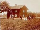 Närkesstuga, tvåvånings enkelstuga.
Familjegrupp, 7 personer framför stugan.
Emil Axelsson