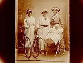 Två kvinnor med cyklar, en kvinna med en barnvagn med ett barn i.Fru Ebba Johansson
