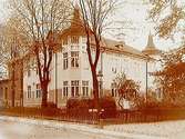 Trähus i två våningar med gul puts med två hörntorn. Hörnfastigheten Alnängsgatan - Olaigatan.