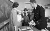 Första spad, Polis i skolorna 13 okt 1967

Polisman håller informationsmaterial i handen som skall delas ut till eleverna. Läraren står vid svarta tavlan.