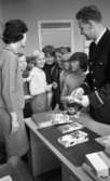 Första spad, Polis i skolorna 13 okt 1967

Polisman håller i informationsmaterial för att ge till eleverna. Läraren står bredvid.