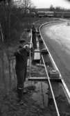 Ervalla översvämning 30 mars 1968

Två män arbetar med ett vägräcke, och på bilden ser man också ett godståg komma vid en järnvägsövergång.