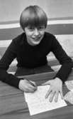 Tolvåring vann verstävling 17 april 1967

En pojke sitter och skriver på ett papper. På bordet ser man en bit av en duk.