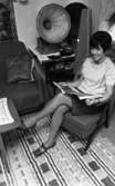 Betania villan 12 oktober 1966

En kvinna sitter på en stol och tittar i en tidning. I rummet ser man också en grammofon på ett bord.