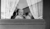 Gyttorp 2 23 februari 1967

I ett fönster med gardiner på en dörr ser man en kvinna och ett litet barn.