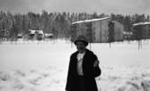 Kopparberg,1 mars 1967. 

En äldre dam står utomhus vid ett bostadsområde i Kopparberg. Hon är klädd i en svart kappa, vit blus, svart kjol och en ljus hatt. 
Märta Bernerhed stående på Kyrkvägen. I bakgrunden syns Källtorpsvägen 6 och 8 på 