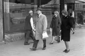 Folk går på systemet, 11 maj 1965. 
Bilden tagen på Drottninggatan, del av apoteket Svanens skyltfönster syns.