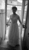 Brudklänning, 19 augusti 1965

En kvinna i brudklänning med slöja och krona därtill står i en entré.