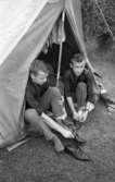 Campingplatsen bra i Gustavsvik 12 juli 1965

Två yngre män sitter i tältöppning och sätter på sig skor