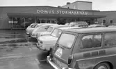Stormarknaden, 31 juli 1965

Entrén till Domus stormarknad en regnig dag. Bilden är tagen på stormarknadens parkering. Flera bilar är parkerade där. Skyltar med texten 
