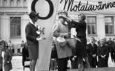 Knytkalaset 5 juli 1965.

Harald Aronsson står på scenen med en korg i händerna, flankerad av de båda värdinnorna, varav den ena håller en prispropeller i händerna. Den andra värdinnan kröner hans hjässa med en krona i form av torn. Publik i bakgrunden.