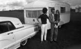 Camping 5 juli 1965.

Familj bestående av far, mor och liten flicka står vid bil med husvagn.