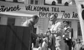 Knytkalaset 5 juli 1965.

Harald Aronsson tilldelas ett standar av en herre med texten 700 år på samt det krönta Ö-et. Jubileumsvärdinna samt publik i bakgrunden.
