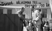 Knytkalaset 5 juli 1965.

Harald Aronsson tilldelas ett standar av en herre med texten 700 år på samt det krönta Ö-et. Jubileumsvärdinna samt publik i bakgrunden.