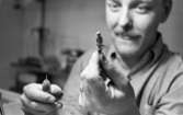 Silversmed 20 augusti 1965

En silversmed håller en liten silverfigur mellan vänstra handens tumme och pekfinger. Figuren har formen av en människa. I högra handen håller han ett verktyg. Svärdbäraren
