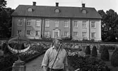 Hasselfors bruk 19 augusti 1965

I förgrunden syns en trädgårdsmästare. Bredvid honom står ett solur. Bakom honom syns en trädgård. I bakgrunden längre bort syns Hasselfors bruksbostad. En trappa i två avsatser som leder upp mot huset syns även samt längre fram i bilden några konstfärdigt klippta buskar till höger.