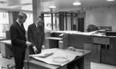 Handelsbanken Fellingsbro 11 december 1965

Två kostymklädda unga män samt en snickare syns på bilden. De båda unga herrarna tittar på en ritning som de har framför sig. Det är inne i Handelsbanken i Fellingsbro. Inredningen är under konstruktion.