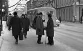Halkiga pensionärer, 18 december 1965

På bilden ett antal personer på trottoaren på Drottninggatan. I förgrunden syns fem män i olika åldrar. En av dem har en käpp i handen. Bakom dem i bakgrunden syns några damer. Ytterligare personer syns på andra sidan gatan utanför Rådhuset. En buss och en bil kör förbi på gatan.