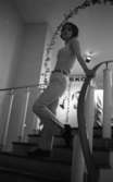 Modebilder 23 april 1966

En mannekäng står i en trappa. Hon är klädd i ärmlös vit blus, vita byxor, mörkt skärp, ljusa strumpor samt mörka skor. Bakom henne syns en dekorativ liten äreport över trappan.