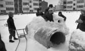 Snögrottor, 4 december 1965.

Man varnar för 'farliga snögrottor' i snöhögarna från snöplogarna. Här bygger barnen en snöfästning på stora cementrör på en fyrkantig innergård omgiven av hyreshus.