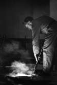 Johnson metall, 21 januari 1966

På bilden syns en metallarbetare iklädd arbetsoverall, livrem och keps  i sitt arbete med metall vid ugnen på 