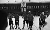 Hot rod, Kungälv - Örebro, 7 januari 1966

På bilden syns sju bandyspelare fotograferade framifrån.
Bildens bakgrund utgörs av ett långt hus med en klocka med poängresultat på huset i centrum. Åskådare syns i bakgrunden. På tröjorna på bröstet på varje spelare står 