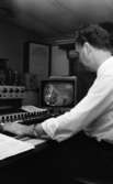 Pensionärspop 2 mars 1966

Man i vit skjorta sitter i ett kontrollrum framför den tekniska utrustningen. En TV syns i bakgrunden.
