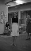 ABF - Norrbysektion, Klänningssömmerskor 21 april 1966

I förgrunden syns en kvinna i svartvit knäkort klänning samt lågklackade skor. Till höger om henne står en annan kvinna i knäkort klänning och lågklackade skor. Hon bär ett långt halsband. Till vänster i bakgrunden sitter en kvinna i blus och knäkort kjol samt skor på fötterna. Tavlor hänger på väggen till vänster om henne.