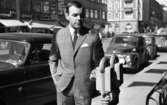 Andersson Gustavsson mode 23 april 1966

En manlig fotomodell visar herrkläder. Han är klädd i kostym, skjorta och slips. Han håller sin vänstra hand på en parkeringsautomat. Bakom honom sitter en person i en bil. Ytterligare bilar samt hus syns i bakgrunden.