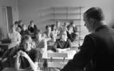 Engelsk lärare 6 april 1966

En lärare i engelska sitter på en skolbänk och blickar ut över och undervisar eleverna i sin klass.















































































































or. Han går nedför en kort trappa utomhus.