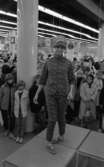 Baddräkter 12 maj 1966

En fotomodell i mönstrad jacka, byxor samt keps på huvudet står på catwalken. Nedanför i bakgrunden syns publik som tittar på.
















































































































or. Han går nedför en kort trappa utomhus.