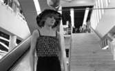 Baddräkter 12 maj 1966En fotomodell i mönstrat linne, svarta trosor samt med hatt på huvudet står på catwalken. I bakgrunden syns en trappa.or. Han går nedför en kort trappa utomhus.