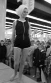 Baddräkter 12 maj 1966

En fotomodell iklädd en genomskinlig svart, ärmlös body med vita kantbårder på samt en virad schal på huvudet går på catwalken. Publik syns i bakgrunden.
















































































































or. Han går nedför en kort trappa utomhus.