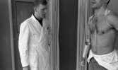 Ortopeden 28 februari 1966

En man med armprotes och bar överkropp syns i förgrunden. Bredvid honom står en ortoped i vit rock.