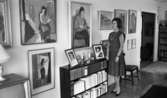 Fru Ring 15 januari 1966

Porträtt av medelålders kvinna som poserar i vardagsrum tittandes på väggens tavlor