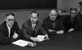 Hallsbergsskottarna 5 januari 1966

Närbild på fyra män som sitter i rad vid konferensbord, framför sig har de papper med text på