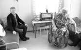 Handikappad får drömbostad 22 januari 1966

Äldre man sittandes på soffa och kvinna i rullstol i rum med soffa och säng, vid fönstret ett bord med radio modell äldre