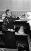 Hattfabrik läggs ned 1 mars 1966

En arbetare på ett hattmakeri plockar på översta hyllan där det ligger en massa hattar.