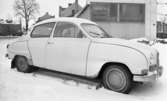 Bilar, Bilnummer, Bilhall 30 mars 1966

En vit bil står parkerad invid ett hus. det ligger snö på marken.