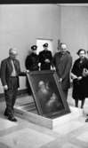Nationalmuseum 1 31 maj 1966

Två herrar håller i en tavla föreställande den gamle Simeon i templet och jesusbarnet. Herrn till höger är klädd i ljus arbetsrock. I bakgrunden står två poliser och tittar på. En kvinna i svart kappa står bredvid den arbetsklädde mannen.
