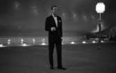 Modenummer 23 april 1966

En man poserar i svart kostym, svarta skor, vit skjorta och svart fluga. Han håller en cigarrett i sin högra hand. I bakgrunden syns en lyktstolpe med en lampa på samt en bassäng. Bilden är tagen inomhus.







































































































































































































































































or. Han går nedför en kort trappa utomhus.