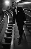 Modenummer 23 april 1966

En man i svart kostym, svarta skor, vit skjorta med svart fluga i halsen håller står framåtlutad och håller i ett räcke bakom sittplatserna på Hjalmar Bergmanteatern. Han står bland rader av sittplatser.






































































































































































































































































or. Han går nedför en kort trappa utomhus.