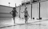 Hej Sommar 3 maj 1966

Två kvinnor - en  i baddräkt och en i bikini håller varandra i händerna och springer genom vattnet i den grunda bassängen i Gustavsviksbadet.








































































































































































































































































or. Han går nedför en kort trappa utomhus.