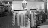 Henning Kjellgrens bageri, 18 april 1966

En ung man i vita arbetskläder samt vit hatt på huvudet håller i en stång varifrån det hänger påsar med texten 