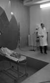 Regionsjukhuset 25 november 1965

En kvinna ligger i en vit rock på en bår under röntgenutrustningen i ett rum på Regionsjukhuset i Örebro. Längre bort står en läkare i vit rock.